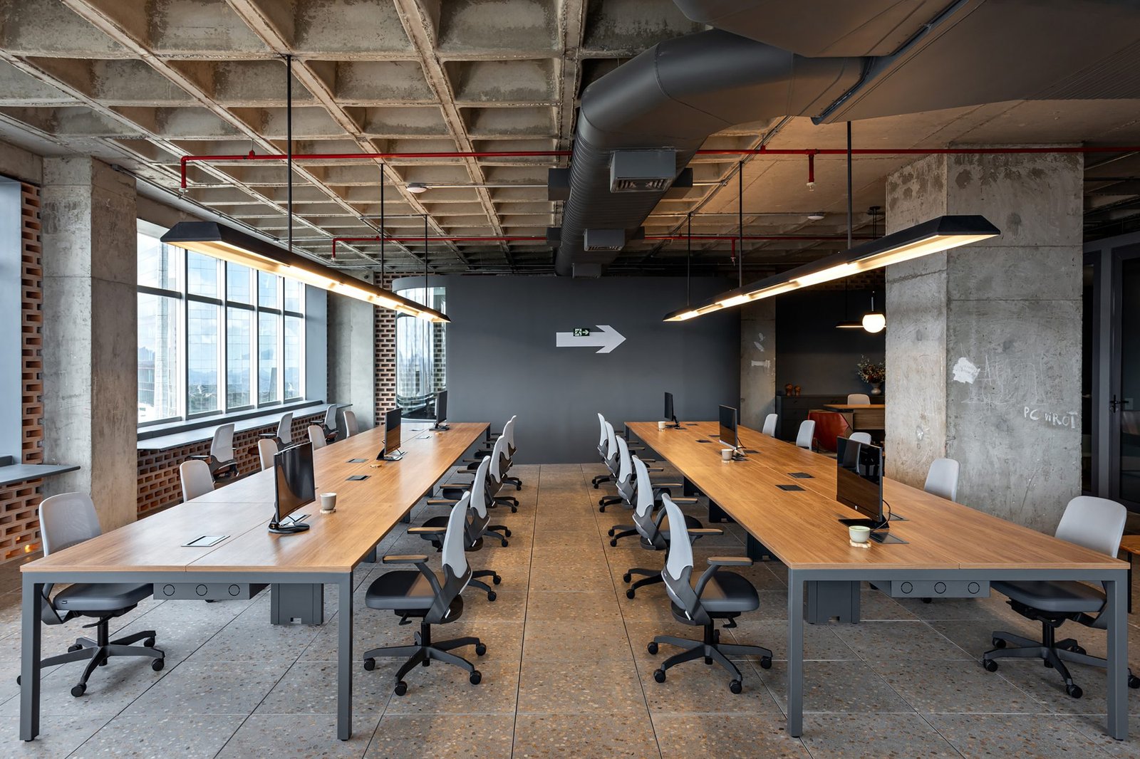 Andar corporativo com bancadas compartilhadas, cadeiras operacionais e iluminação linear.
