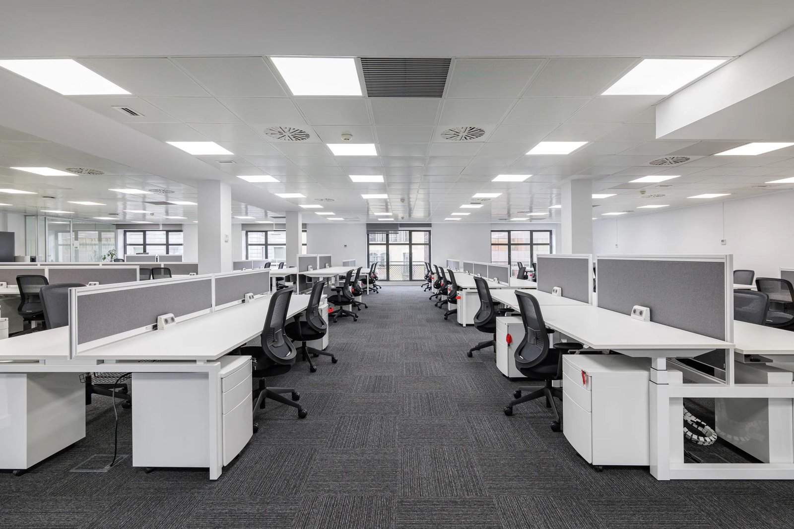 Ambiente corporativo entregue, com estações de trabalho, divisórias baixas, cadeiras operacionais e teto técnico.
